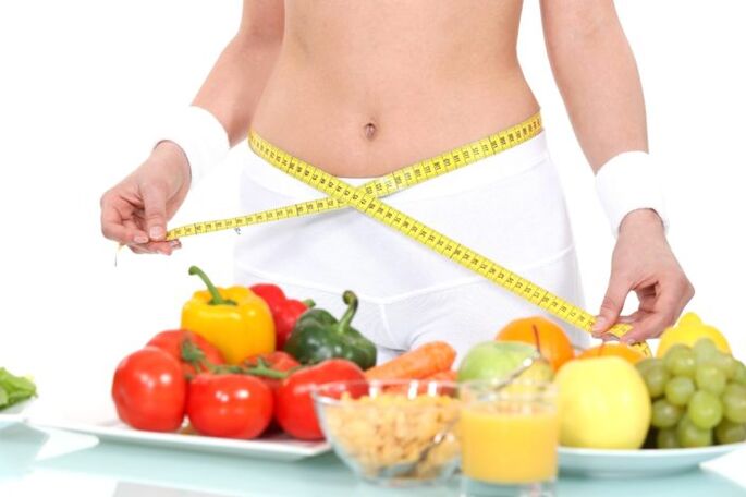 La ragazza misura la vita sullo sfondo del cibo